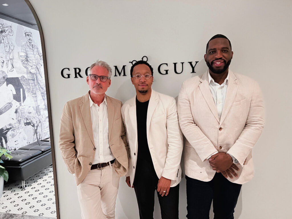 Three well-dressed men standing in front of Groom Guy, showcasing their professional yet approachable style. The image highlights Groom Guy's commitment to high-quality grooming services and customer-focused experience, as seen through the team's polished and coordinated appearance.